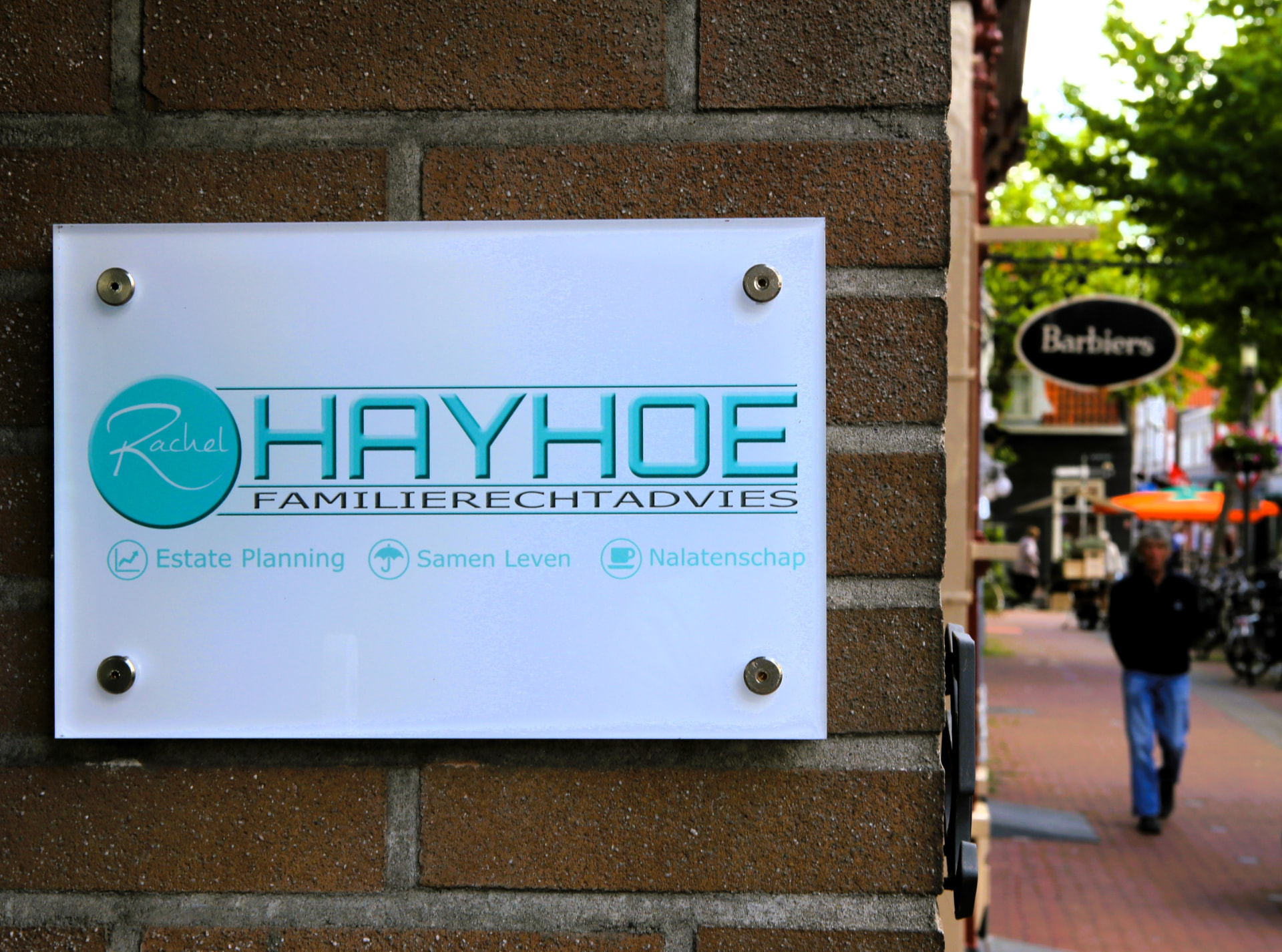 Naambordje van Hayhoe Familierechtadvies met de winkelstraat in Purmerend op de achtergrond